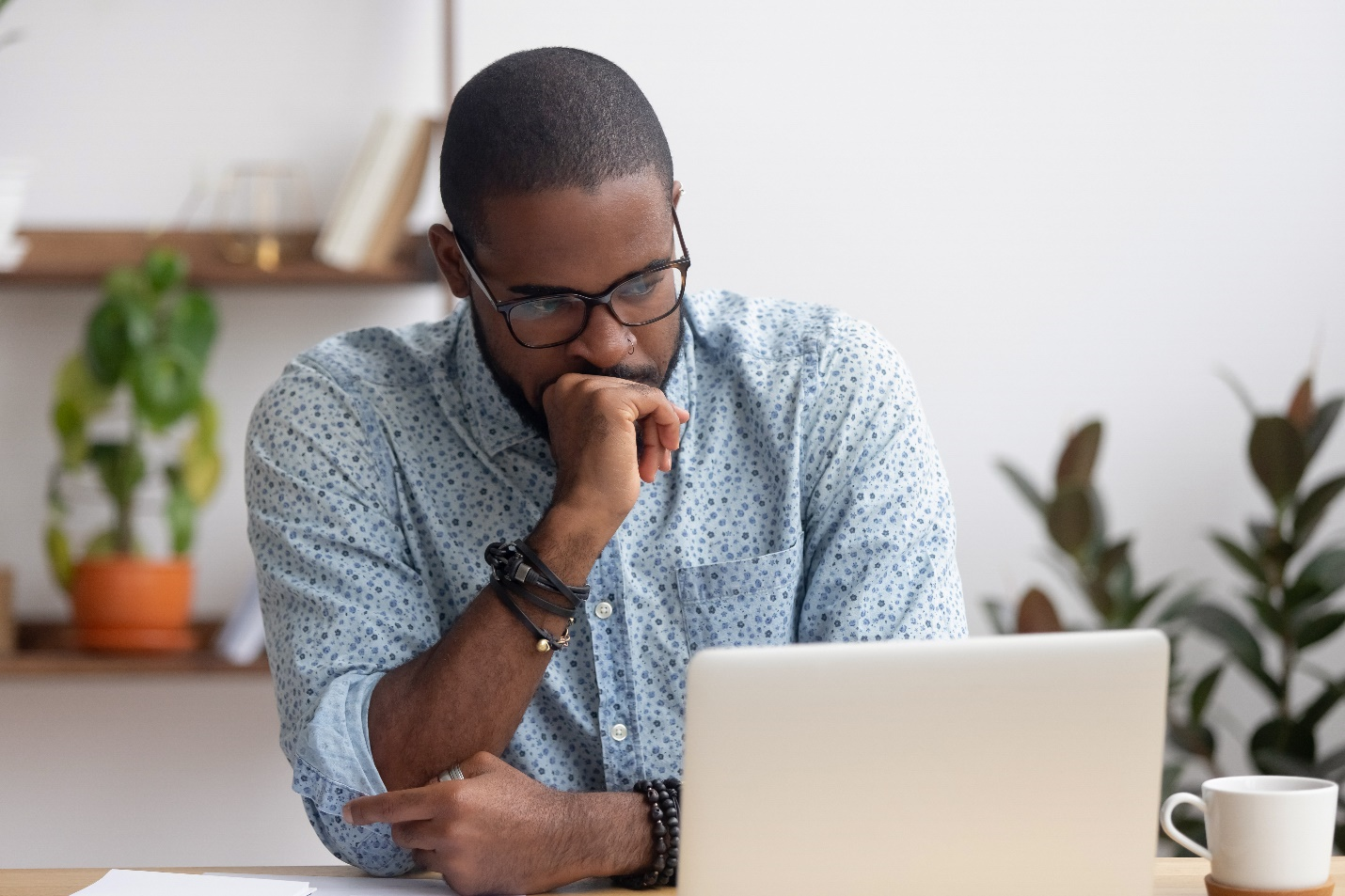 Photo d’un jeune homme assis au bureau, regardant un ordinateur portable.