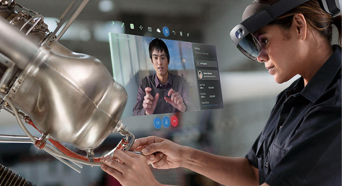 Photo d’un utilisateur HoloLens effectuant une réparation mécanique tout en utilisant Remote Assist pour communiquer avec un collègue.