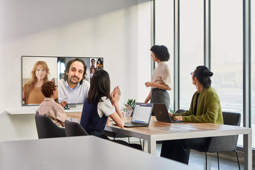 Photographie montrant des personnes dans une réunion vidéo virtuelle dans une salle de conférence.