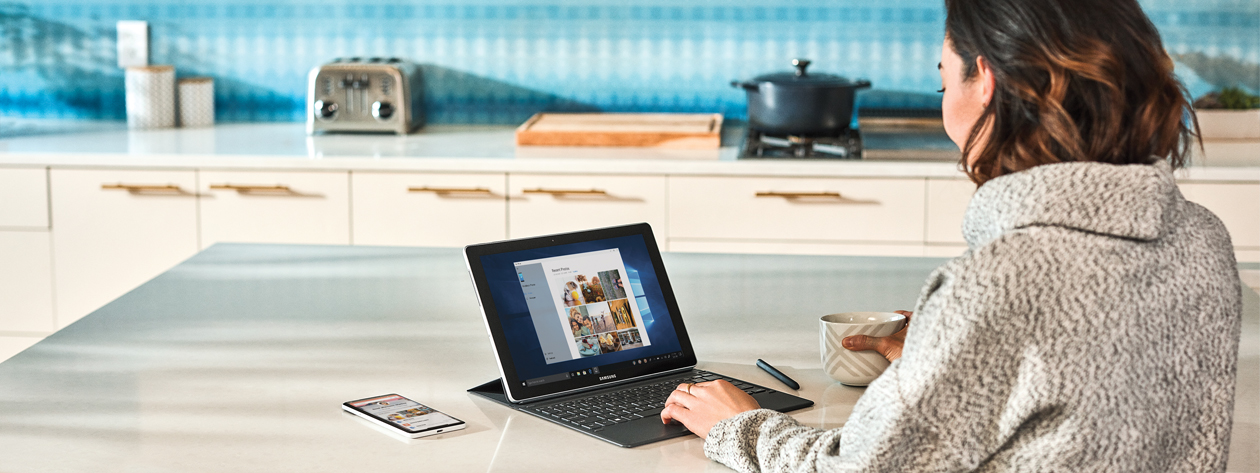 Fotografia de uma mulher usando um dispositivo Microsoft Surface em uma cozinha.