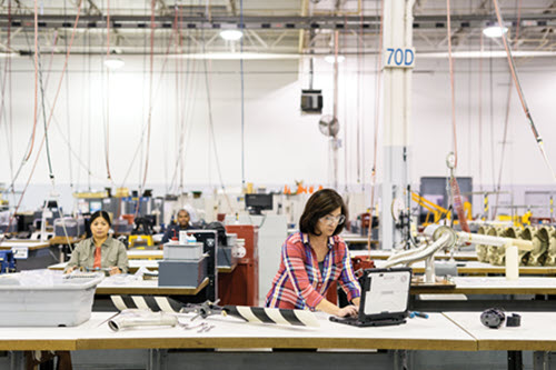 顯示製造業女人正在桌上電腦工作的照片。